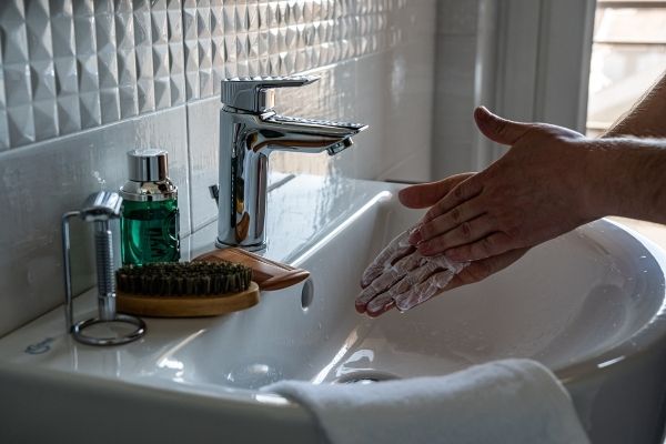 Earth Day- A person scrubbing soap on their hands with the water tap off