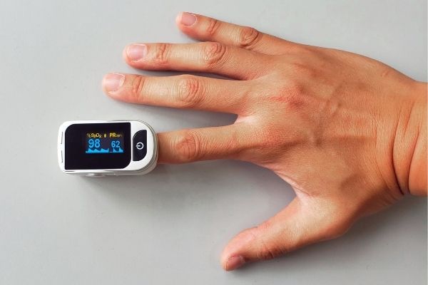 Self-isolation checklist: A person's hand wearing an oximeter