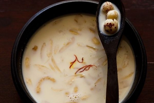 Makhana kheer in a black bowl with some makhanas in a spoon