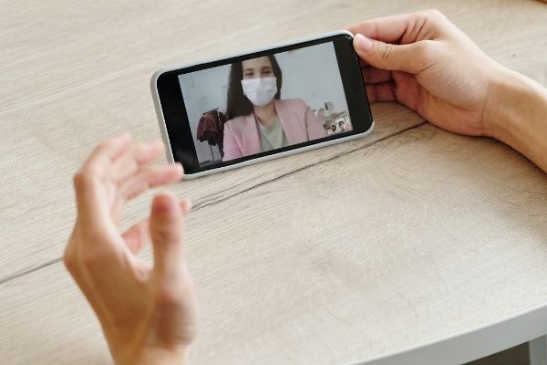 A woman wearing a mask is on a video call