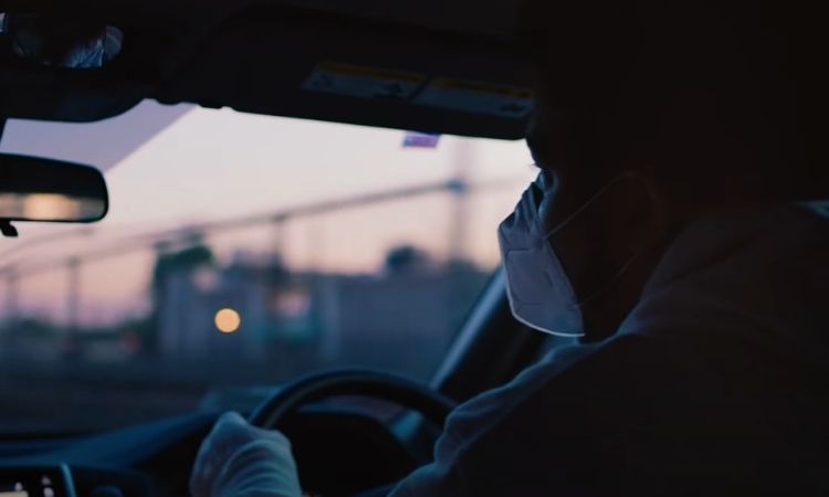 An Uber driver wearing a mask and gloves in a cab