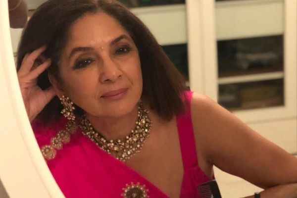 The stunning Neena Gupta in a pink saree, looking into the mirror