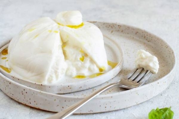 Soft Cheese: A block of Burrata cheese kept in a plate with a fork next to it