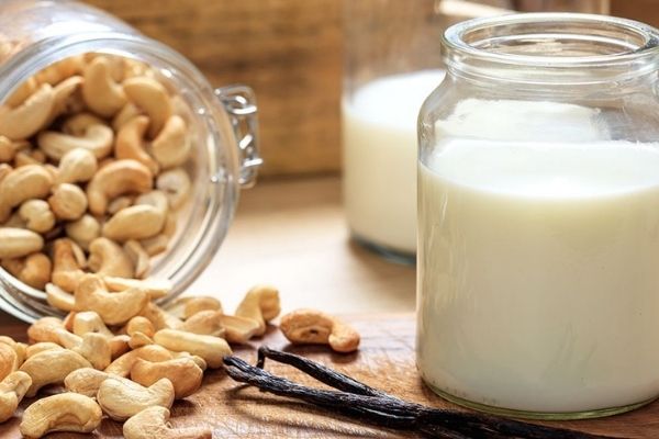 A glass jar with dairy-free cashew milk and cashews on the side