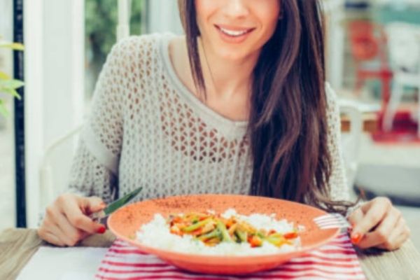 A woman enjoying her meal with rice and vegetables